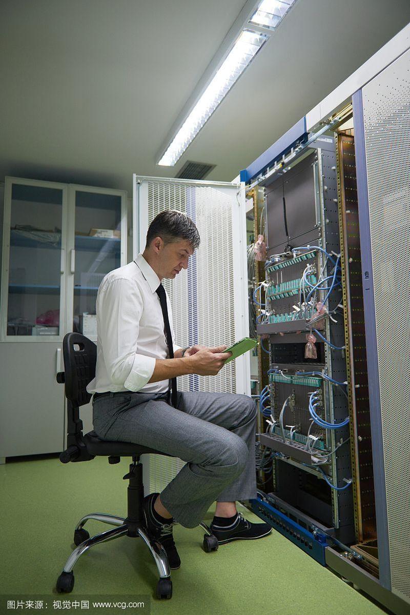 在服务器机房工作的网络工程师,在平板电脑上工作的企业商务人员